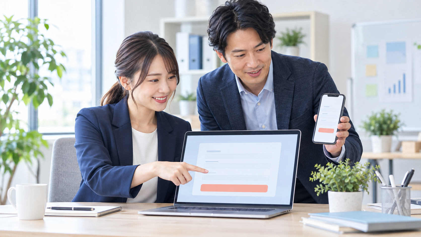 ノートパソコンとスマートフォンで問い合わせフォームを確認する中小企業の担当者